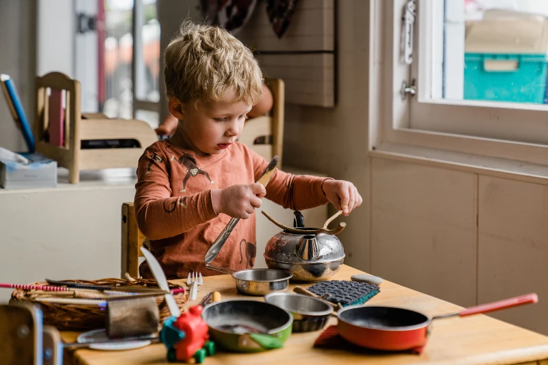 Kindergarten boy playing with toy pots and pans 